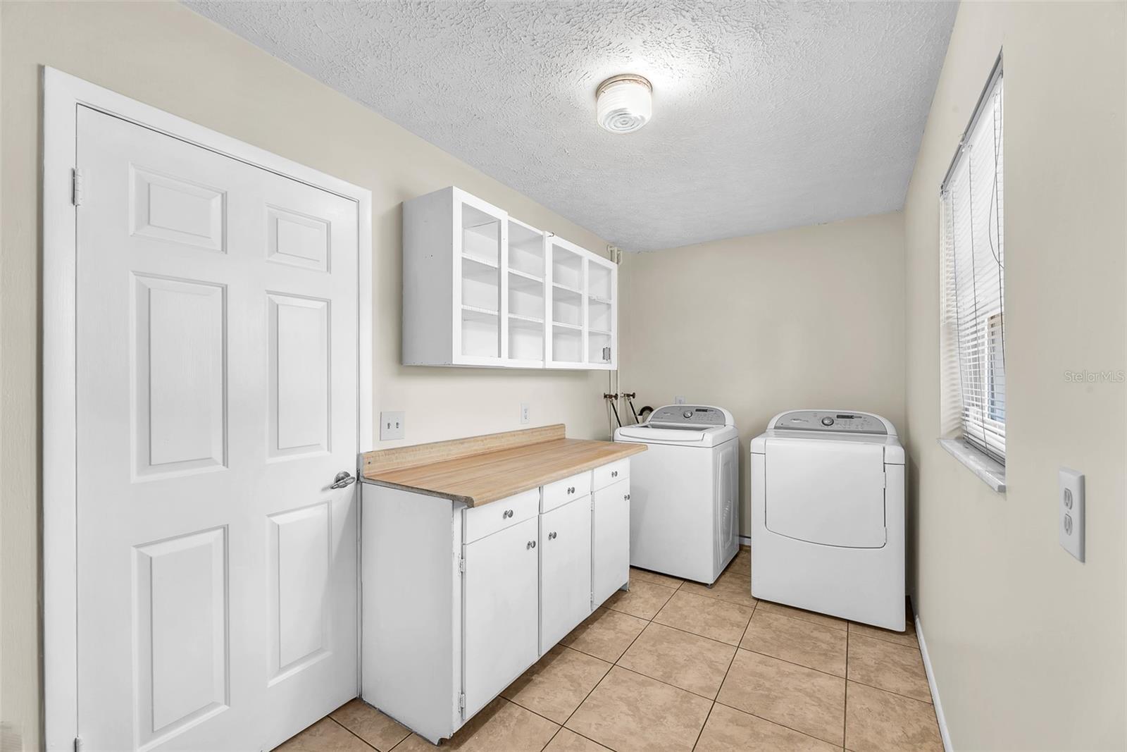 A spacious utility room just off the kitchen is complete with newer washer and dryer, built-in cabinetry, and a pet door that leads to a unique breezeway