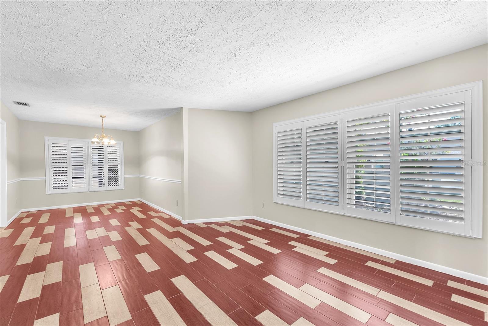 The living and dining area is spacious and filled with natural light streaming through stylish plantation shutters.  The flooring is a durable wood grained tile.
