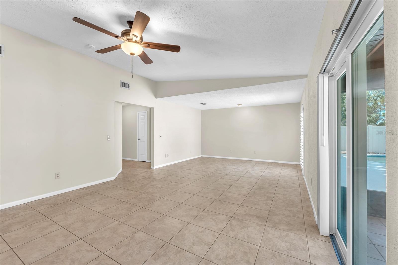 The spacious family room opens through sliding glass doors to a screened porch and private in-ground pool, creating a seamless indoor-outdoor flow that's perfect for relaxing or entertaining.