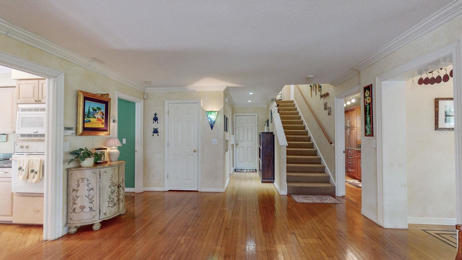 Entrance door hidden right, entrance to wet bar and laundry room just right of stairs to second floor, kitchen left and office/downstairs master green wall, straight ahead door to garage