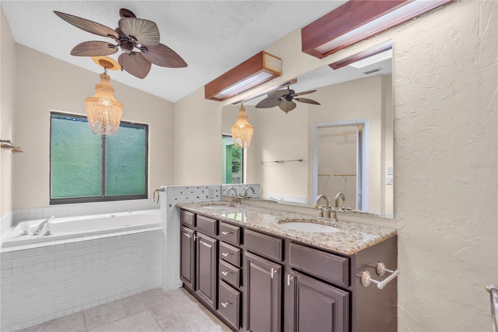 Master Bathroom with whirlpool tub, dual vanities, granite countertop, and ceiling fans. Redone tile floors.