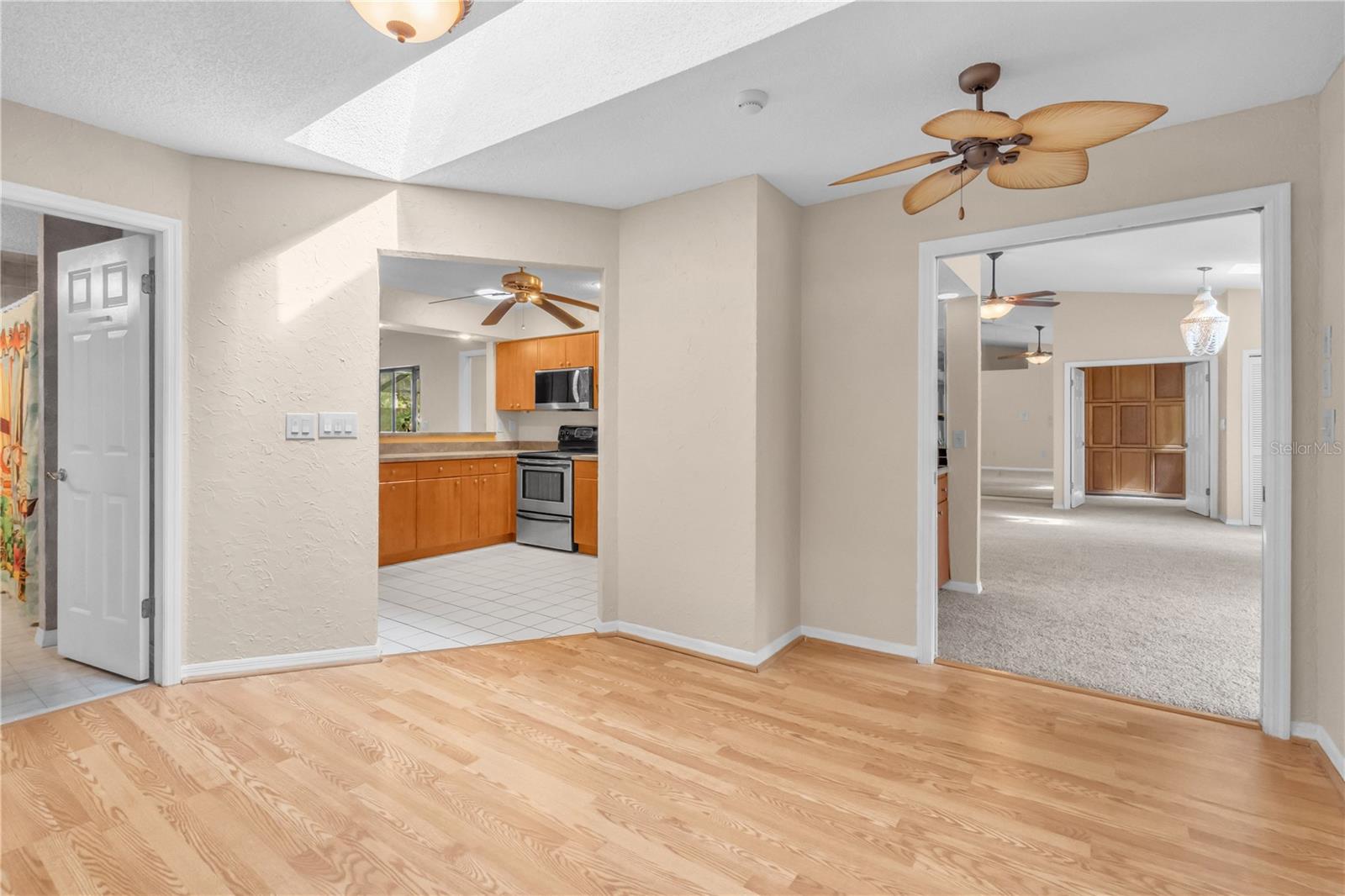 Hallway to Kitchen, Bathroom 2, and Dining Room illuminated with a skylight.