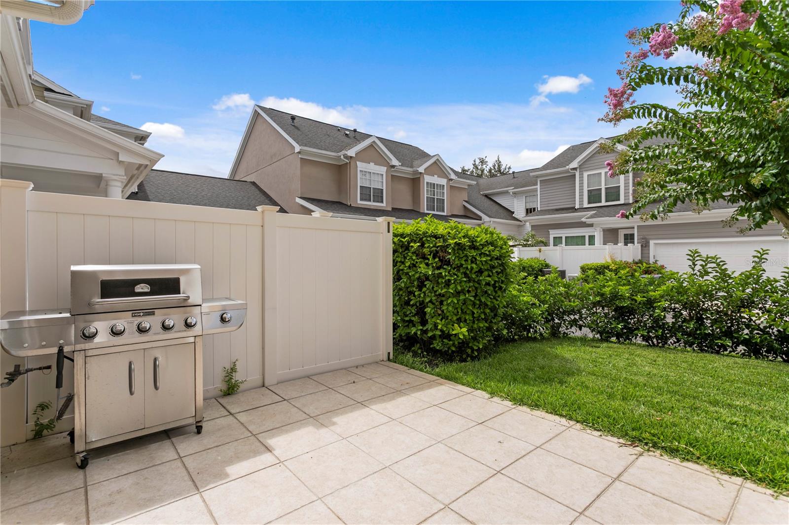 Outdoor patio space with room for a grill, seating, and grass for pets to run around