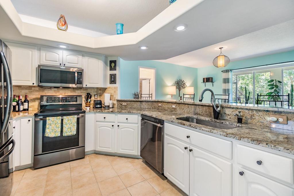 At the heart of the home, the kitchen is perfectly positioned between the formal dining room and the living room. Partial-height walls and decorative high shelves define the space while preserving an open, airy ambiance from front to back. The kitchen is well-appointed with stainless steel appliances, a pantry, updated countertops, and a raised breakfast bar that opens to the living room—ideal for casual dining or keeping conversations going while you prepare meals.