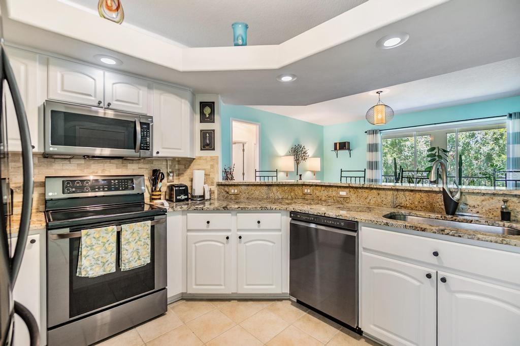 At the heart of the home, the kitchen is perfectly positioned between the formal dining room and the living room. Partial-height walls and decorative high shelves define the space while preserving an open, airy ambiance from front to back. The kitchen is well-appointed with stainless steel appliances, a pantry, updated countertops, and a raised breakfast bar that opens to the living room