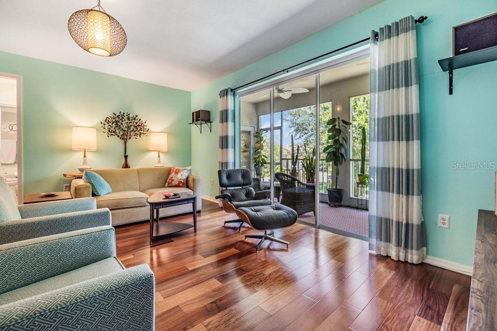The spacious living room offers a welcoming gathering space and features triple-pocket sliding glass doors that lead to a screened-in patio.