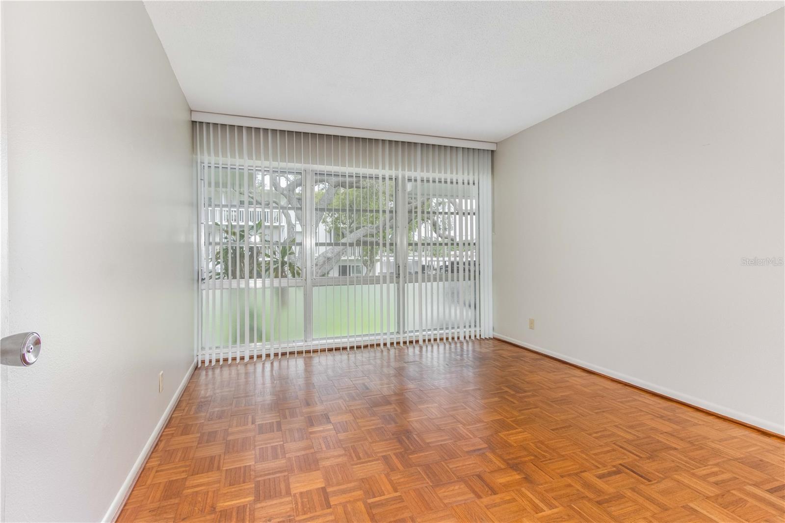 Bedroom with vertical blinds and fresh paint.
