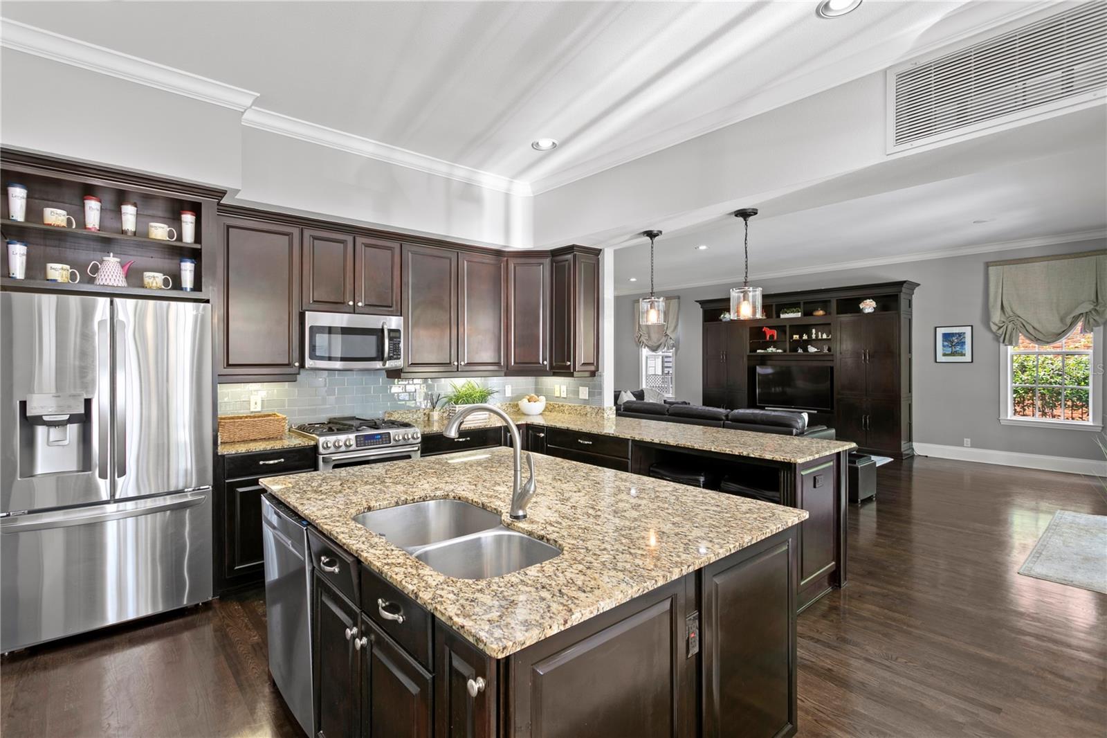 The chef’s kitchen is a true showpiece—featuring a spacious center island, generous storage with two separate pantry spaces, gas range and ovens, oversized refrigerator, and a custom bar area with icemaker and wine/beverage refrigerator—making entertaining both elevated and effortless.