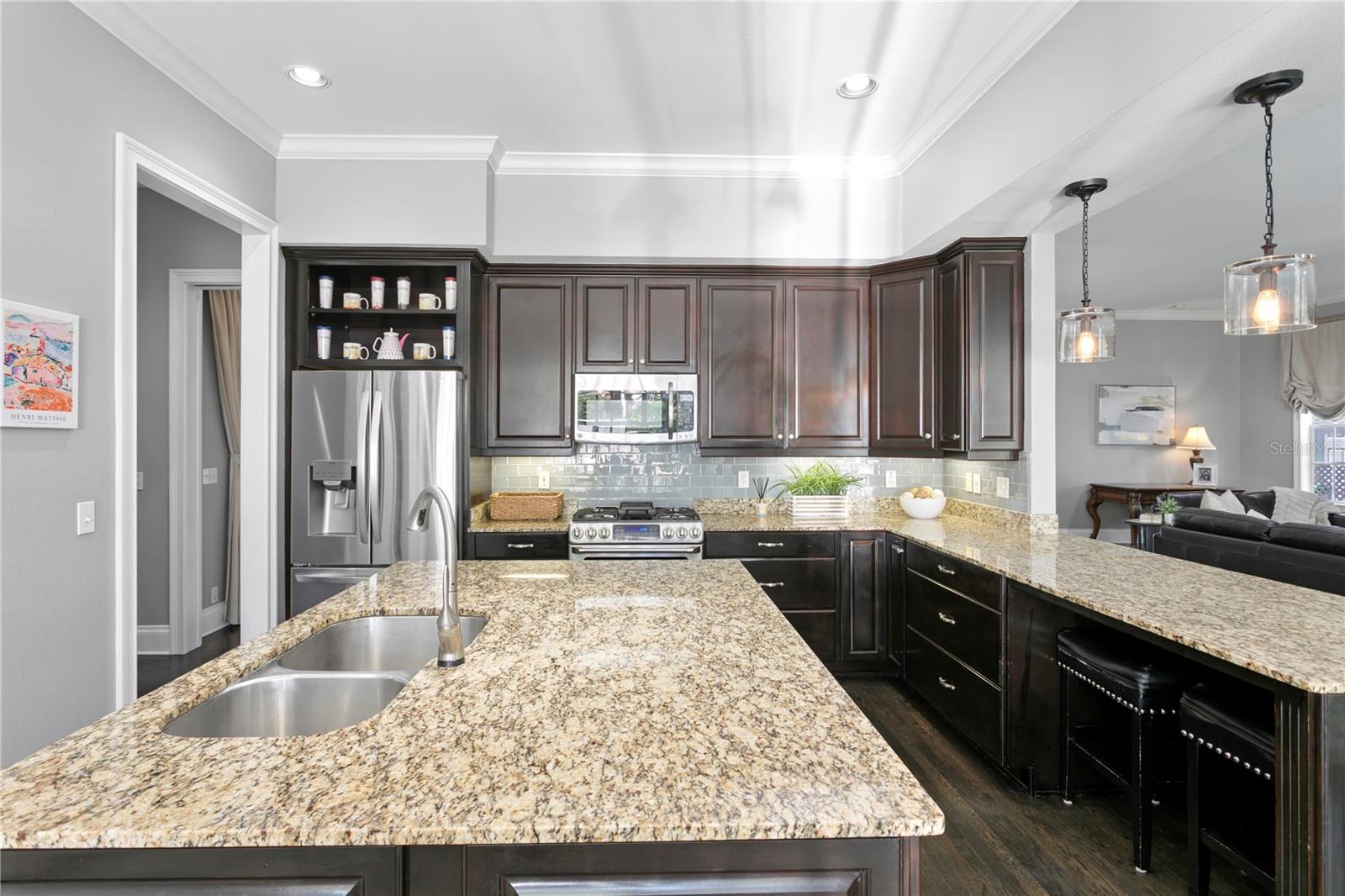The chef’s kitchen is a true showpiece—featuring a spacious center island, generous storage with two separate pantry spaces, gas range and ovens, oversized refrigerator, and a custom bar area with icemaker and wine/beverage refrigerator—making entertaining both elevated and effortless.
