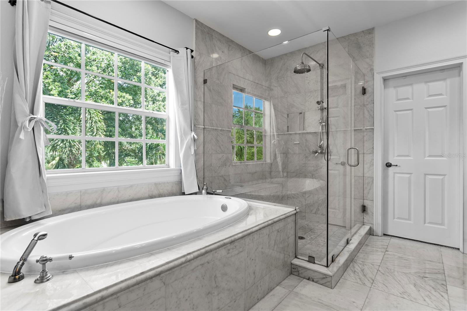 The marble-clad ensuite bath boasts dual vanities, a luxurious soaking tub, and an oversized walk-in shower.