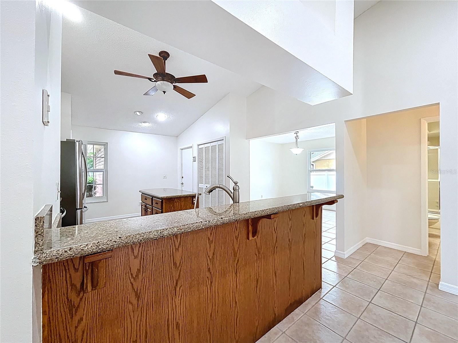 The heart of the home, this open kitchen showcases wood cabinetry, granite countertops, and a raised breakfast bar that connects seamlessly to the living and dining spaces.
