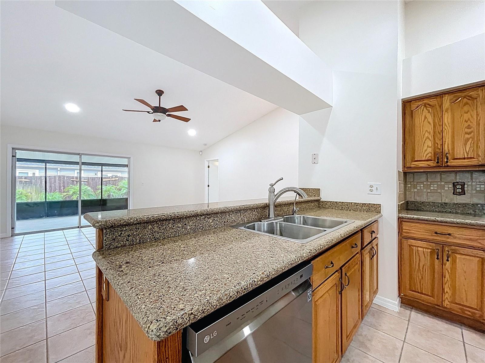 From the dual basin sink and granite bar, enjoy sightlines to the spacious family room and access to the screened patio beyond.