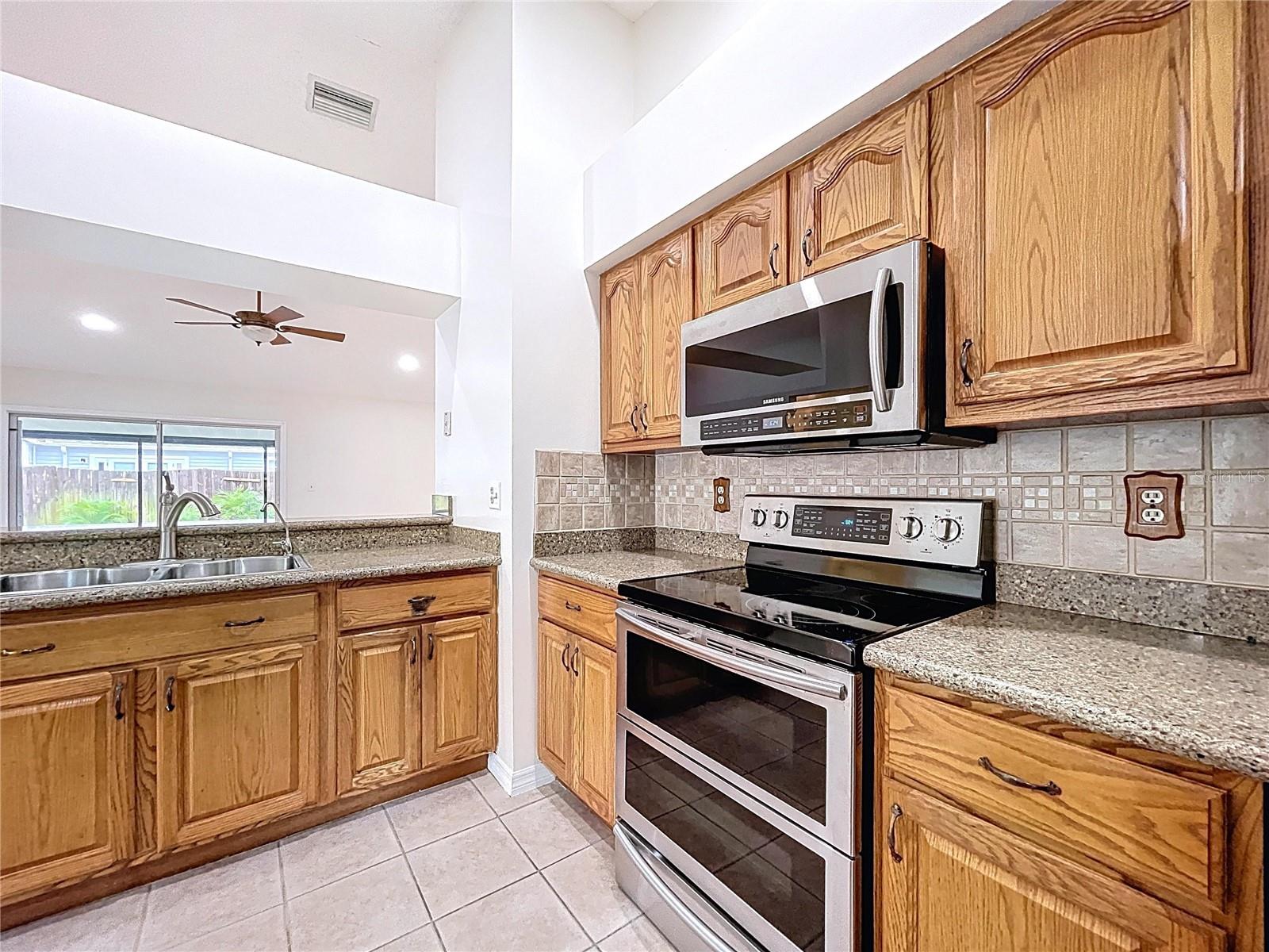 A closer look at the stainless steel Samsung range and microwave, surrounded by ample cabinetry and a stylish tile backsplash.