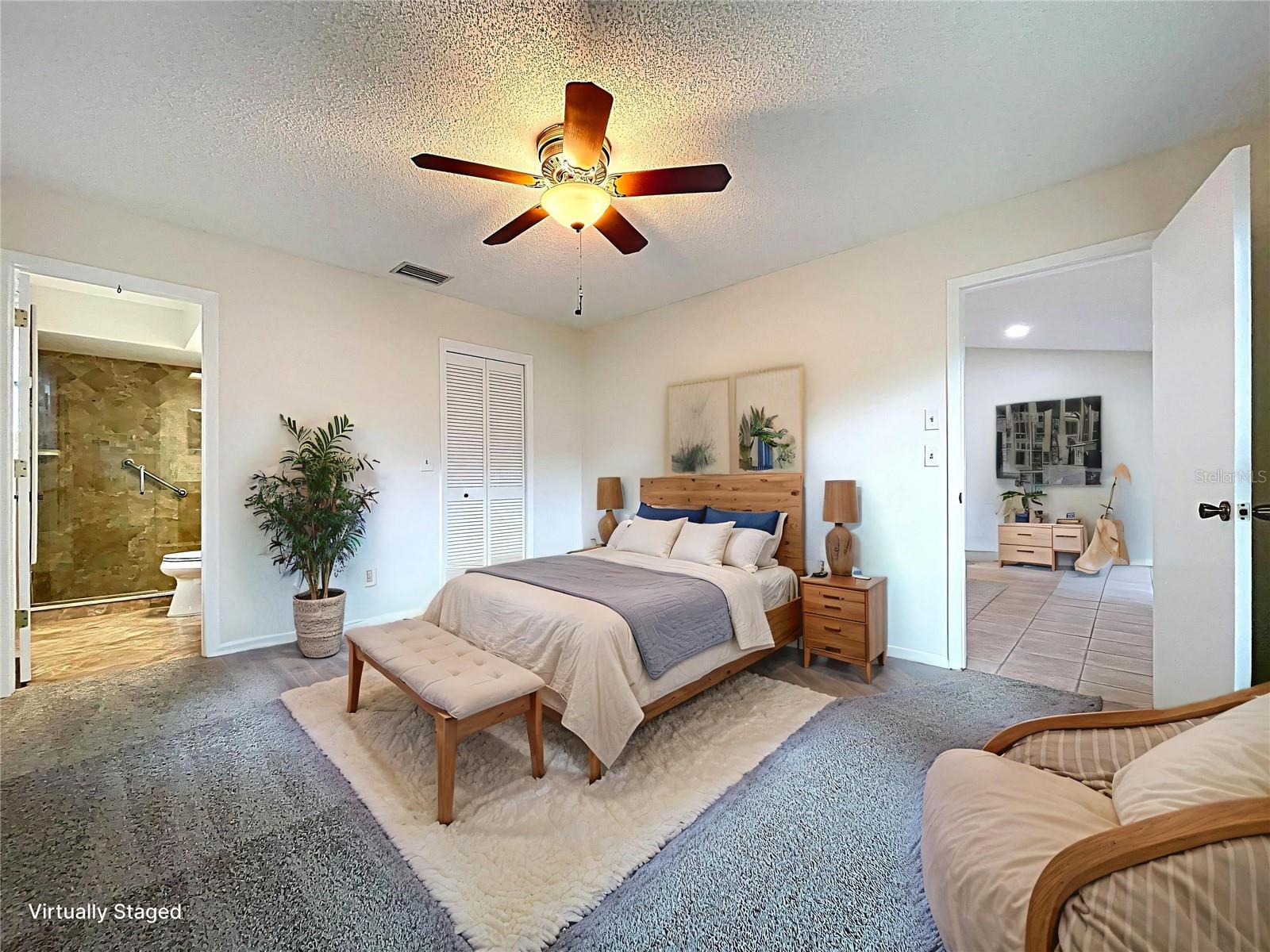 This spacious retreat is styled to highlight its generous proportions, featuring a ceiling fan, large windows, and plush carpeting. A perfect setting for rest and relaxation with direct access to the en suite bath and walk-in closet.