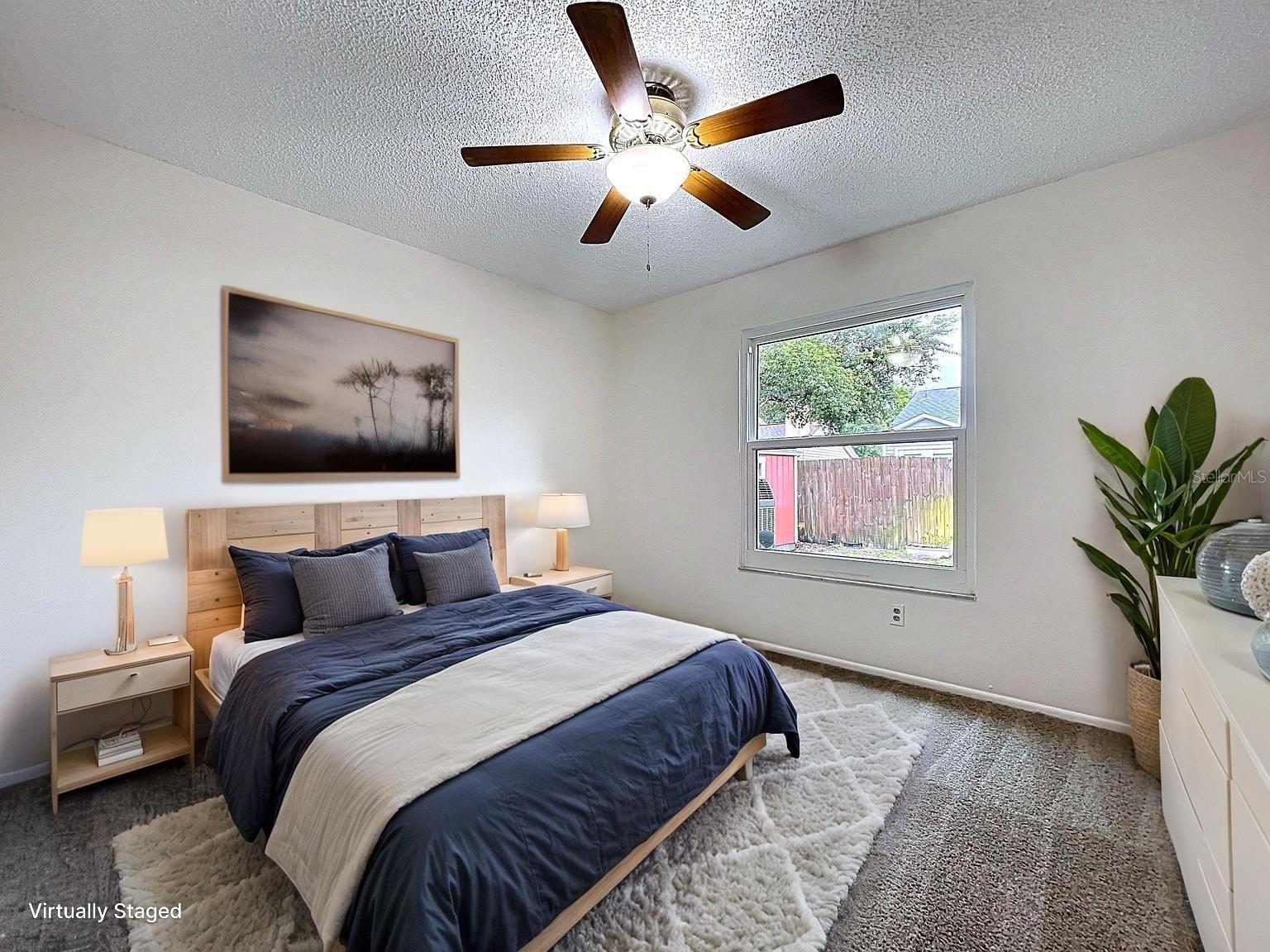Located near the full guest bath, this comfortable bedroom features plush carpeting, a ceiling fan, and a large window offering views of the backyard.