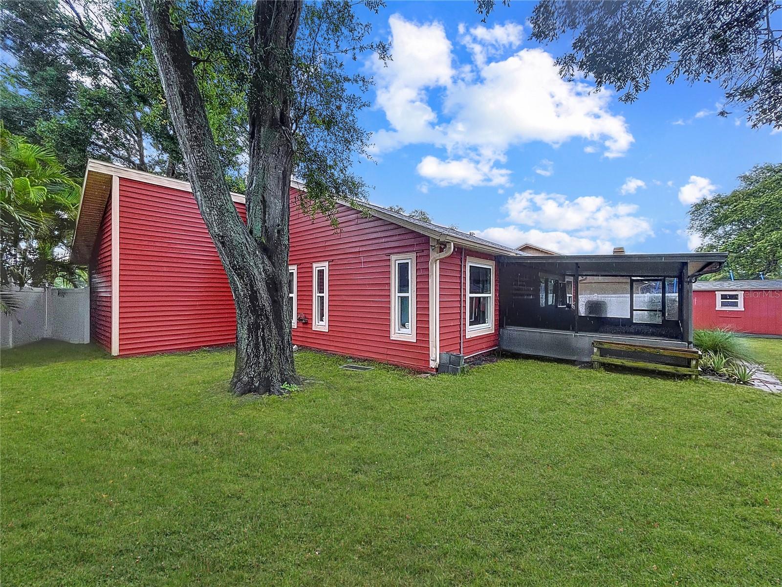 Spacious backyard shaded by mature trees, offering ample room for outdoor activities or future enhancements. A screened-in patio extends from the main home for all-weather enjoyment.