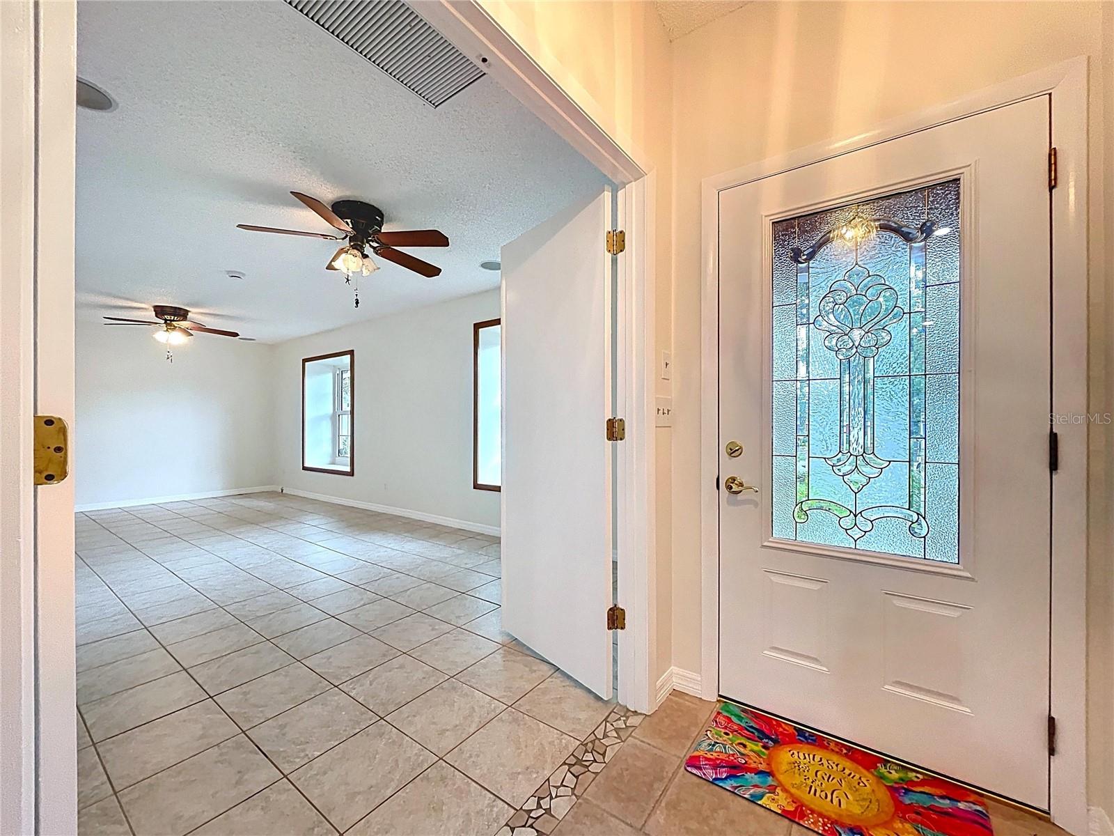 A decorative leaded glass front door welcomes you into a bright, tiled entryway that flows effortlessly into the living spaces.