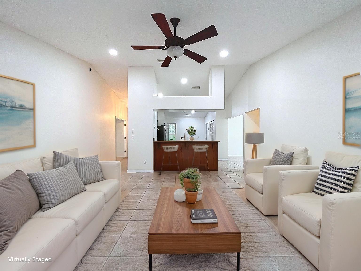 Virtually staged to show a casual coastal vibe, this open-concept living area boasts vaulted ceilings, recessed lighting, and ample room for entertaining.