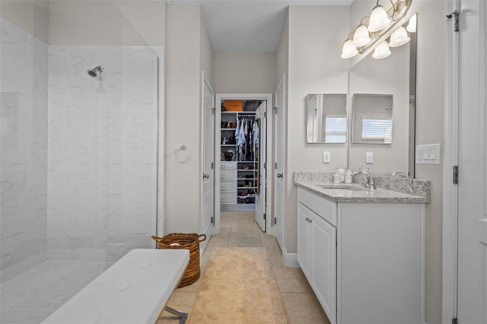 Primary En Suite bathroom featuring super shower with 2 showerheads, split vanities, and walk in custom closet with built ins