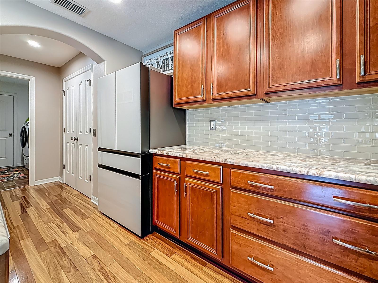 Kitchen features SAMSUGN Extra-large capacity 4-Door French Door Refrigerator with customizable and changeable door panels available in a variety of colors and finishes. A revolution in convenience and design, the concealed Beverage Center™ features both a water dispenser and AutoFill Water Pitcher.  Plus a Dual Ice Maker with cubed ice and Ice Bites™