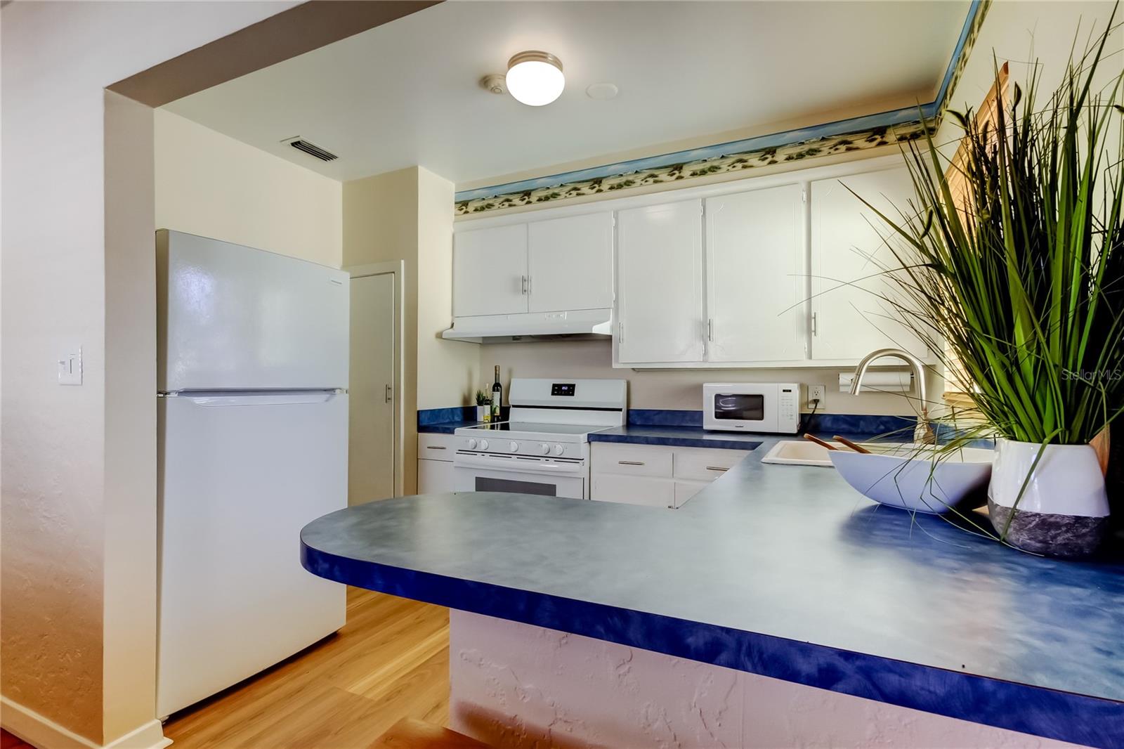 Kitchen showing refrigerator, pantry, range, range hood and microwave.