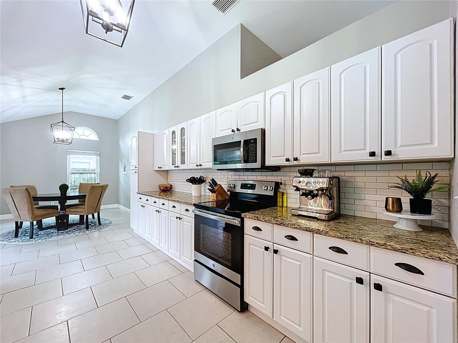 Clean lines and continuity stand out in this layout, with pendant lighting, full-length cabinets, and tasteful tile backsplash adding charm and function.