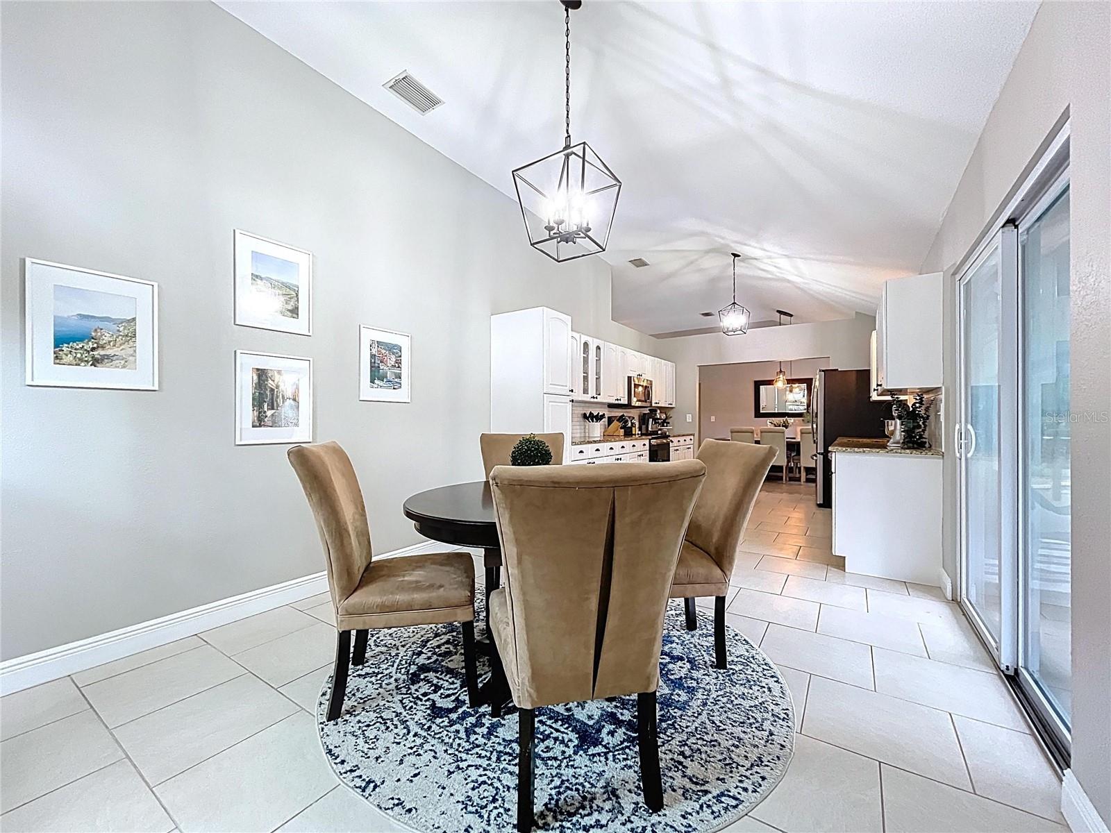 Cozy breakfast nook accented by a round table and warm tones, perfectly framed by large windows and backyard views.