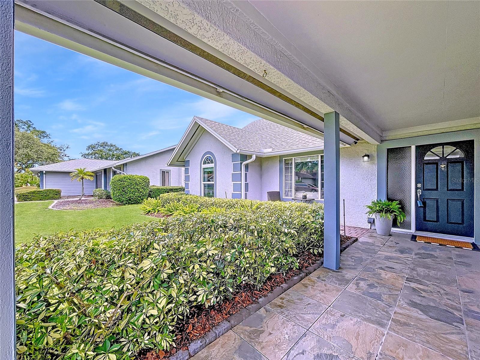 The slate-tiled front porch offers a serene space to sit and enjoy the neighborhood, framed by well-maintained hedges and updated exterior lighting.