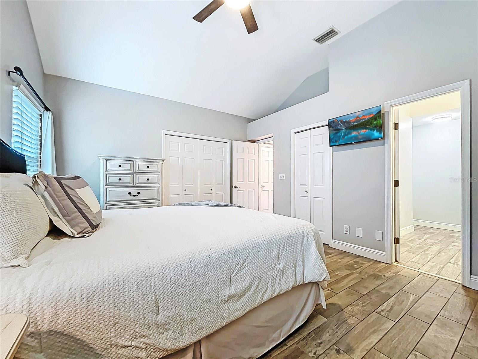 Another angle reveals easy en-suite access, double closet doors, and a mounted TV for convenient relaxation.