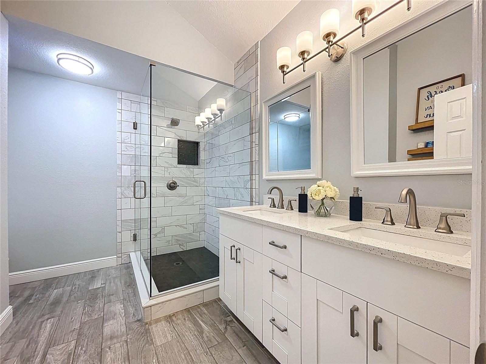A beautifully appointed bath with frameless glass shower, sleek fixtures, and a clean, modern design.