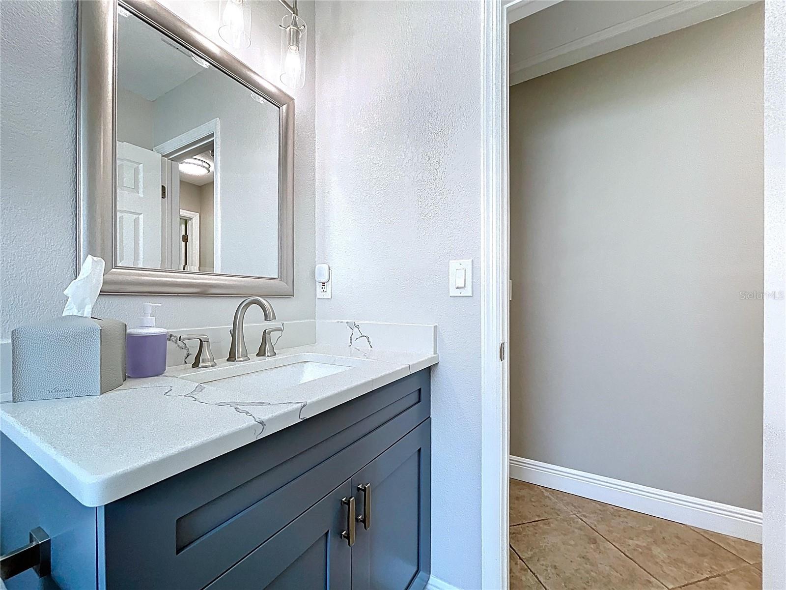 Modern guest bathroom with a sleek quartz countertop, brushed nickel fixtures, and a soft color palette that enhances the bright, clean aesthetic.