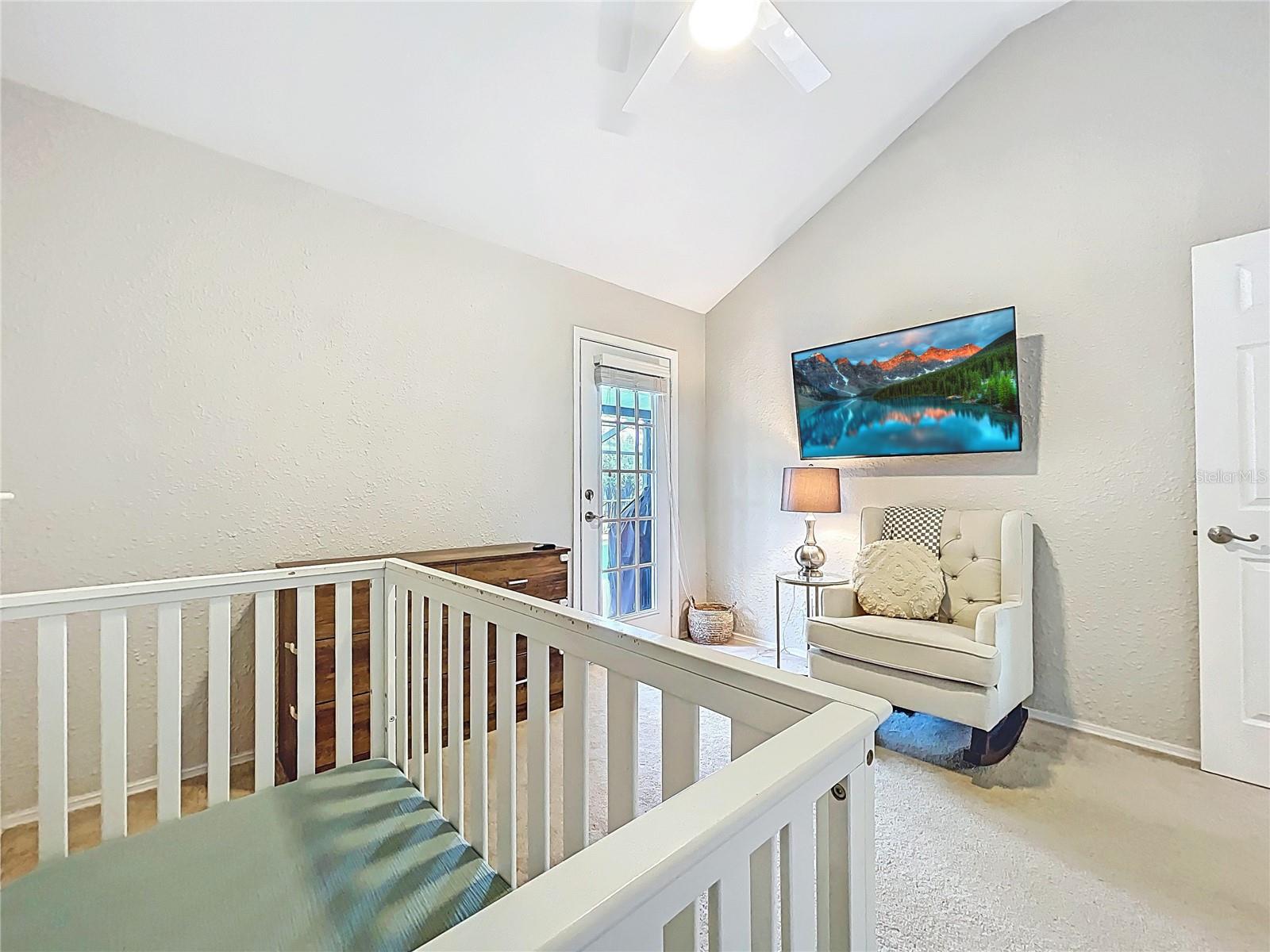 Currently styled as a nursery, the 3rd bedroom offers soft carpeting, vaulted ceilings, and French door access to the backyard—ideal as a bedroom or flex space.