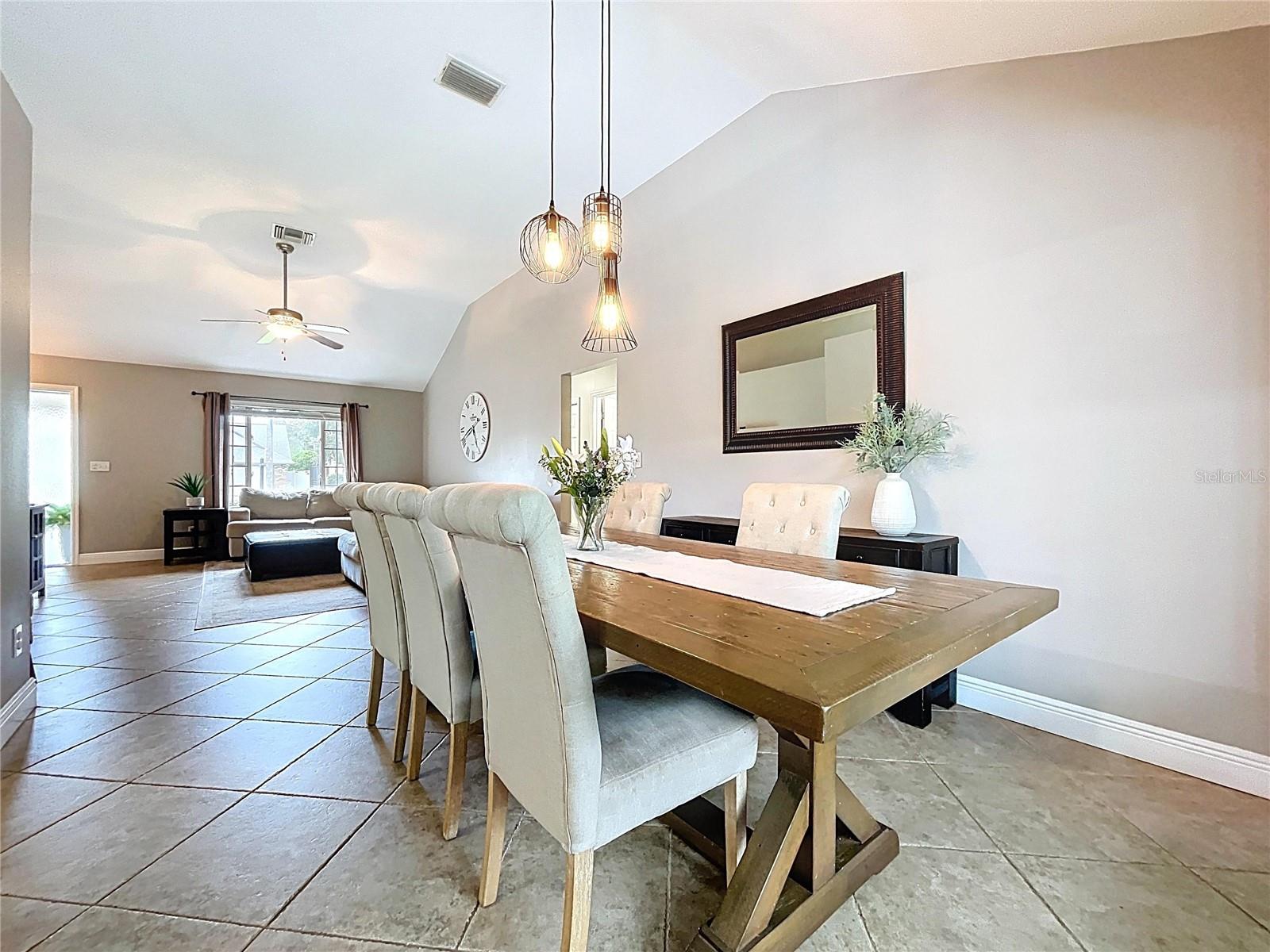 Elegant dining room featuring a rustic wood table, tufted chairs, and modern pendant lighting. Perfectly positioned between the living room and kitchen for easy hosting.