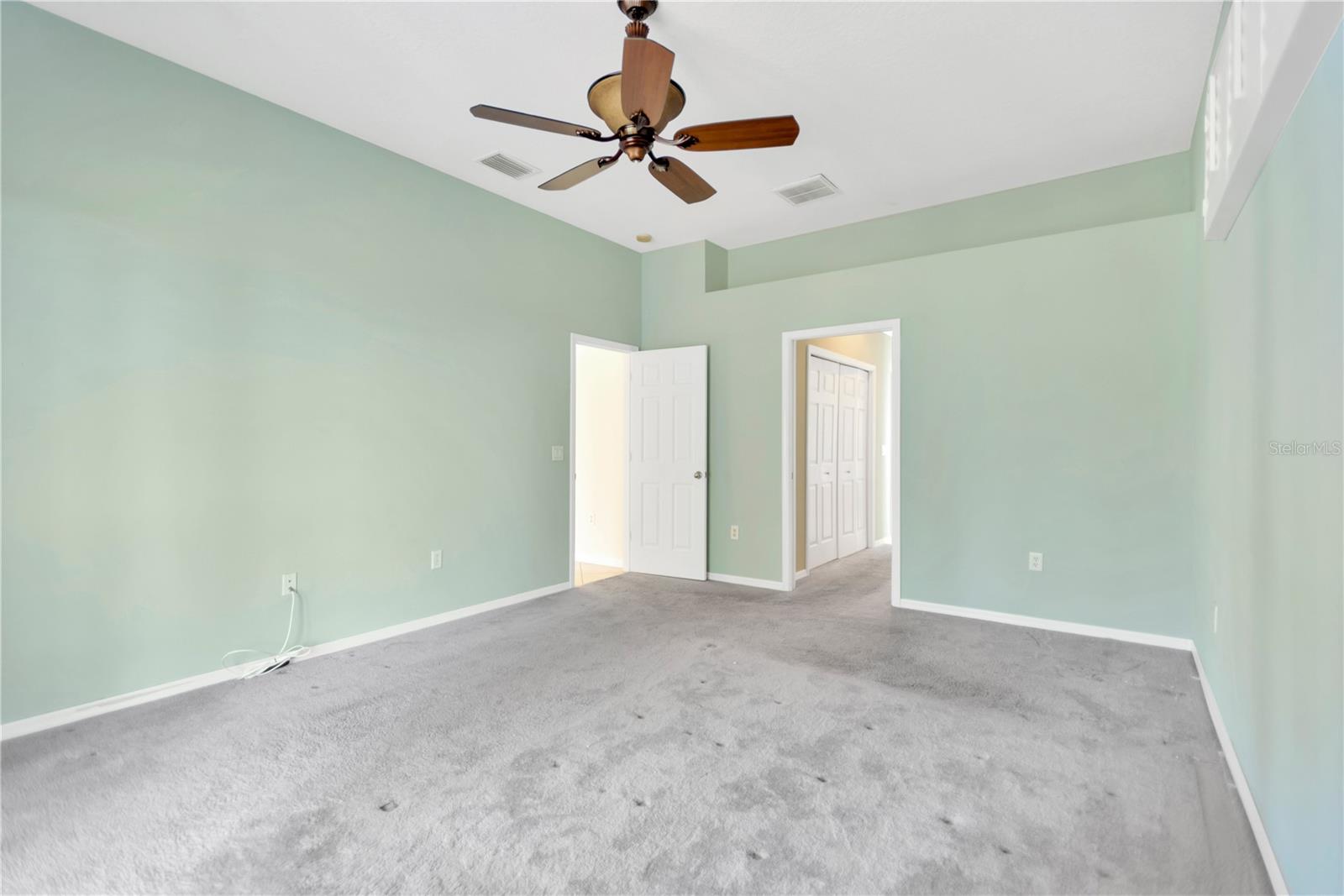 Another look at the primary bedroom with door into the en suite bath and closets.