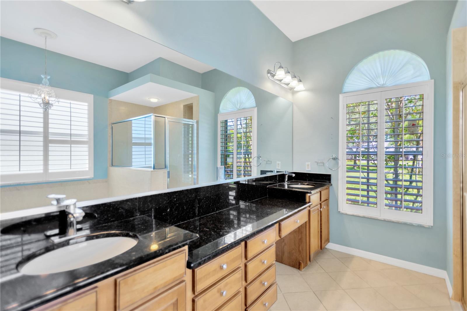En suite with double sinks and vanity area has lots of storage area.