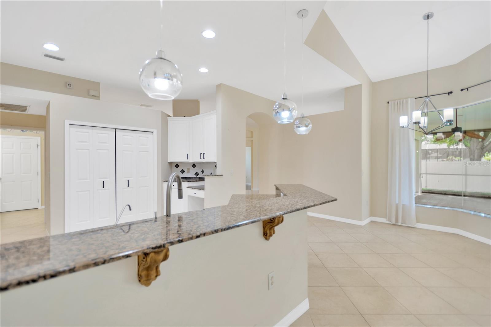 Nice granite breakfast bar for extra kitchen seating. Notice the double door pantry and handy desk area.