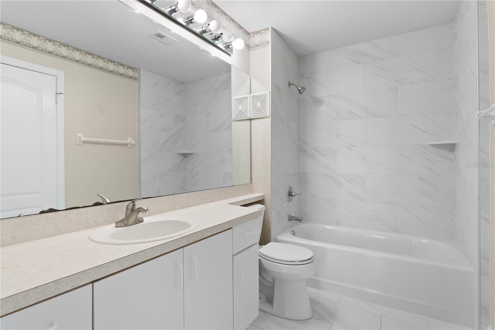 Bathroom has been thoughtfully updated with new large-format floor tile, a contemporary tub and shower.
