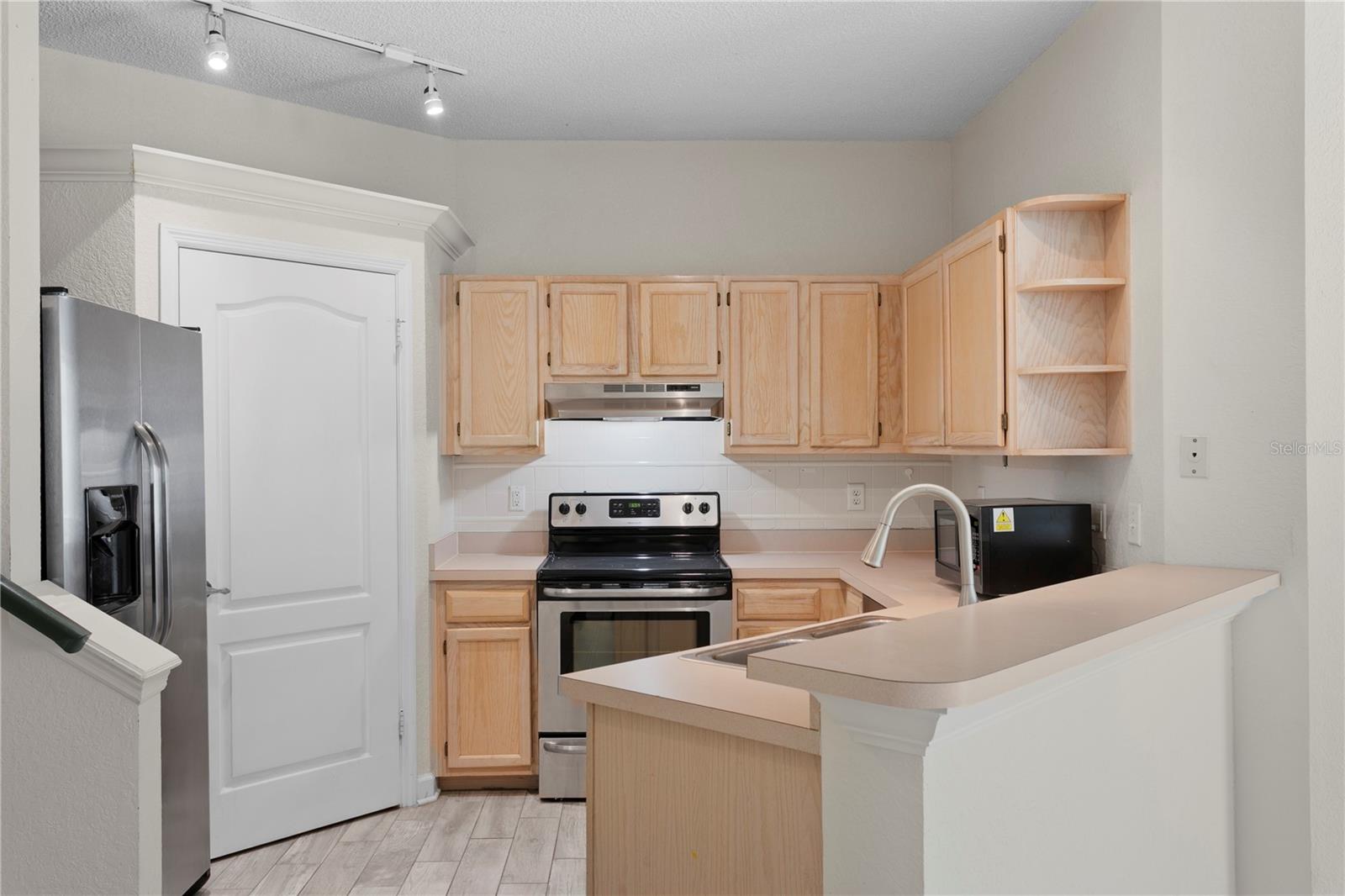 The kitchen is equipped with stainless steel appliances and a generous pantry,