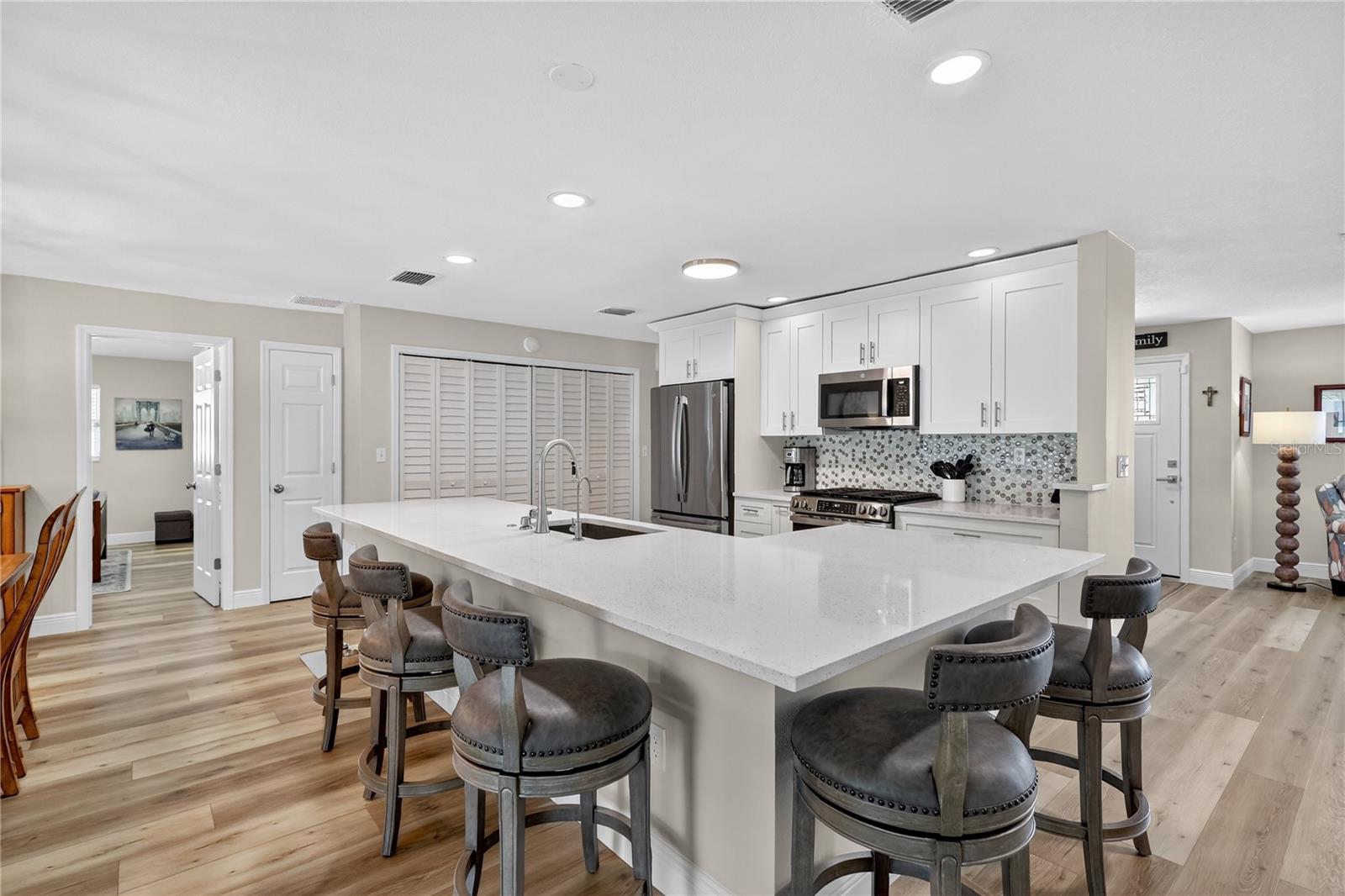 Open modern kitchen topped with quartz counters.