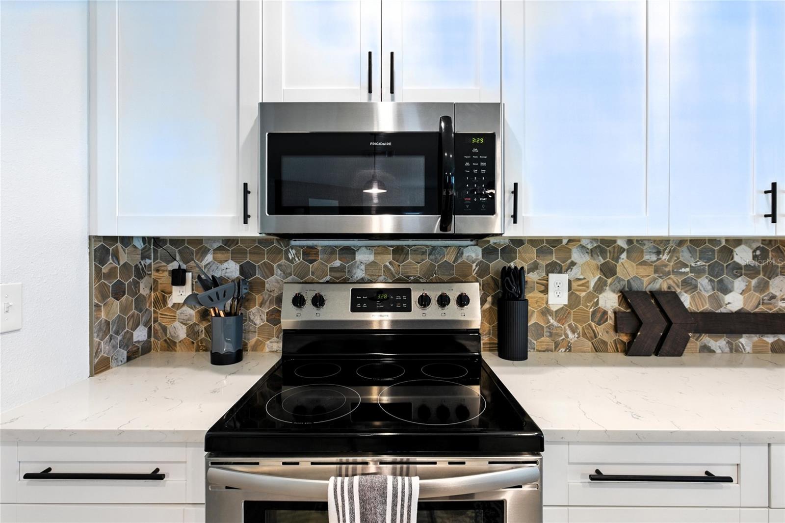Custom backsplash adds a modern edge with mixed tones and texture—definitely not your standard white subway tile. It's a statement piece that elevates the whole kitchen