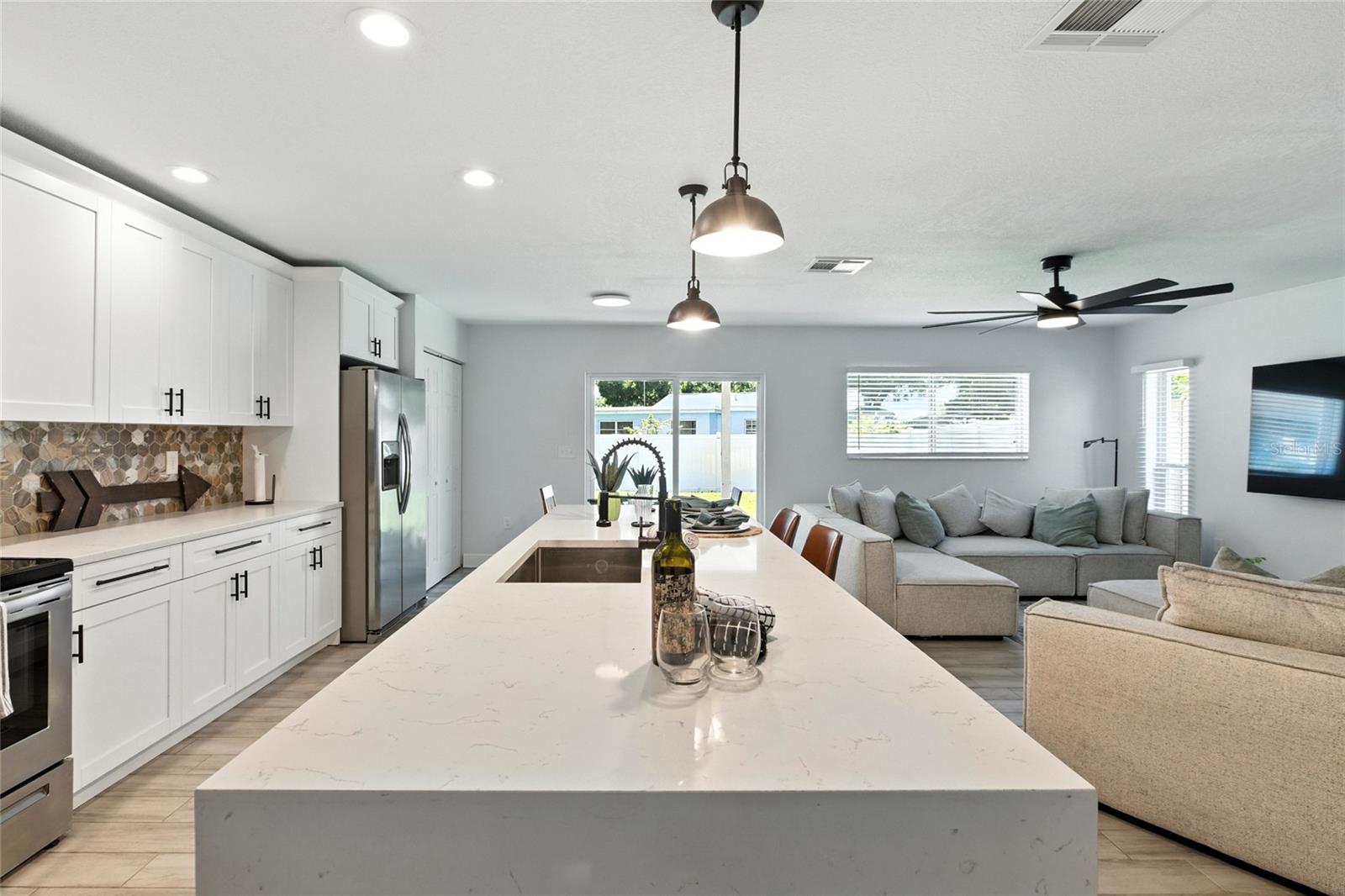 The oversized island is the true centerpiece—perfect for entertaining, casual meals, or homework while dinner’s being prepared! Wide open flow connects seamlessly to living and dining.