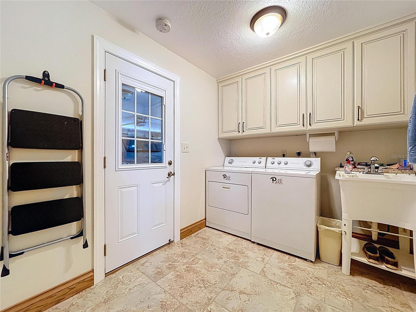 An inside laundry room is a MUST-HAVE in Florida!  This large laundry room offers plenty of storage space as well as a utility sink.