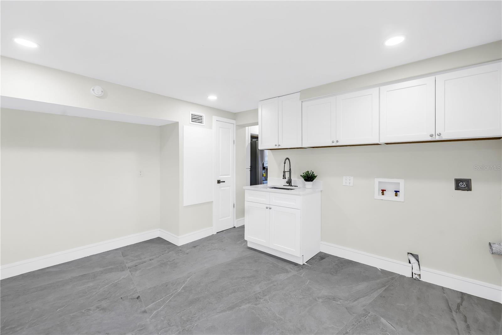 The expansive laundry room provides ample storage, extra pantry space, and a convenient utility sink.