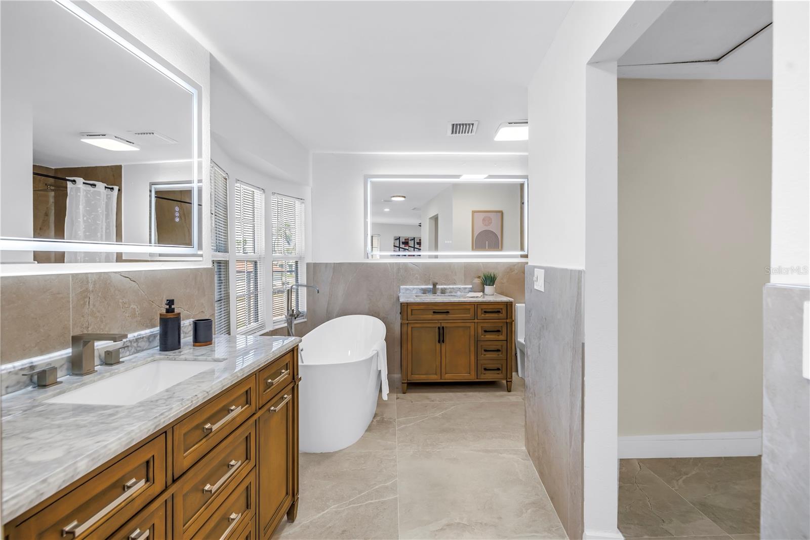 Primary bathroom offers a soaking tub, two vanities and a walk-in rain head shower.