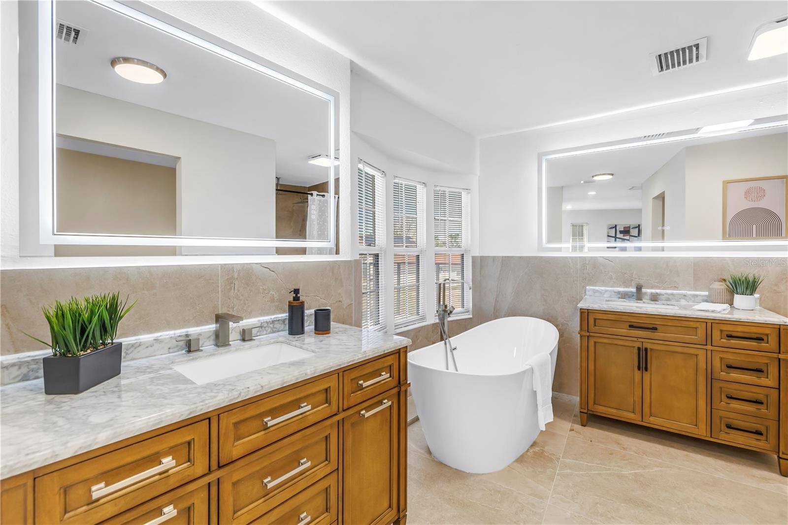 Primary bathroom offers a soaking tub, two vanities and a walk-in rain head shower.