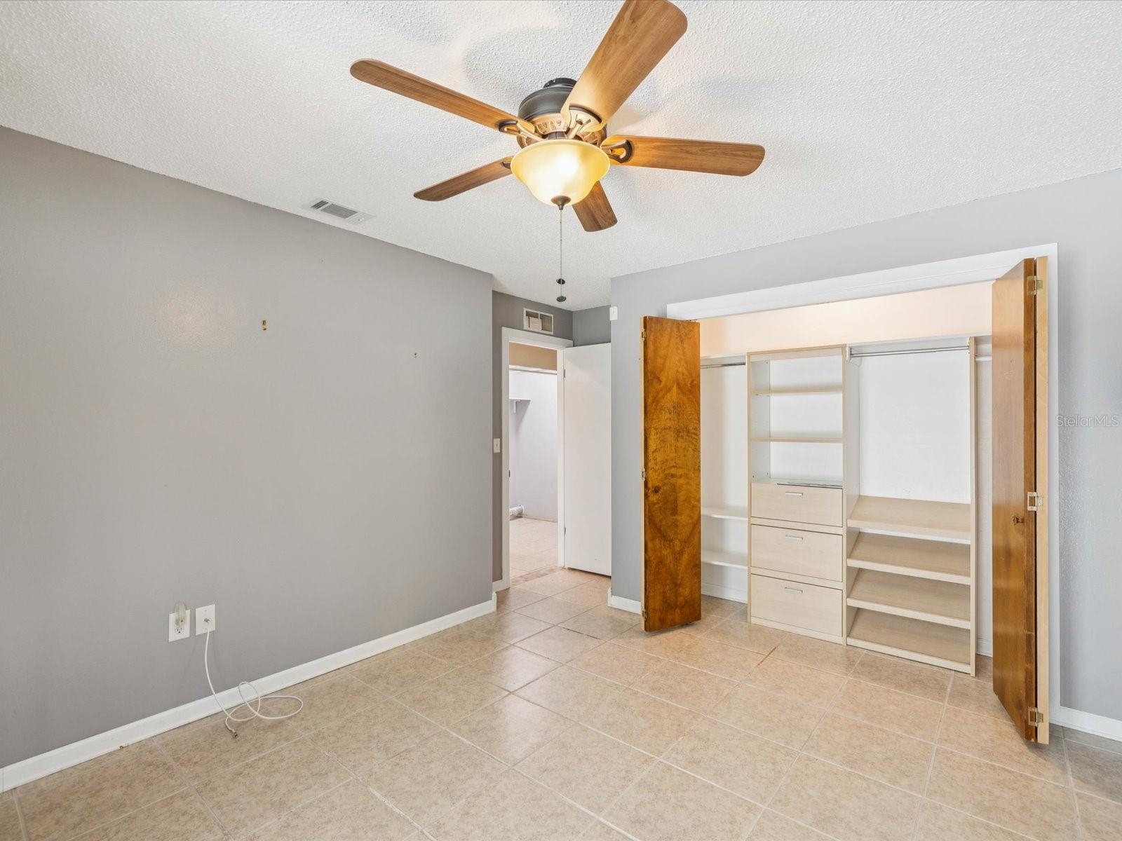 Large second bedroom with custom cabinetry in the closet and outdoor patio access