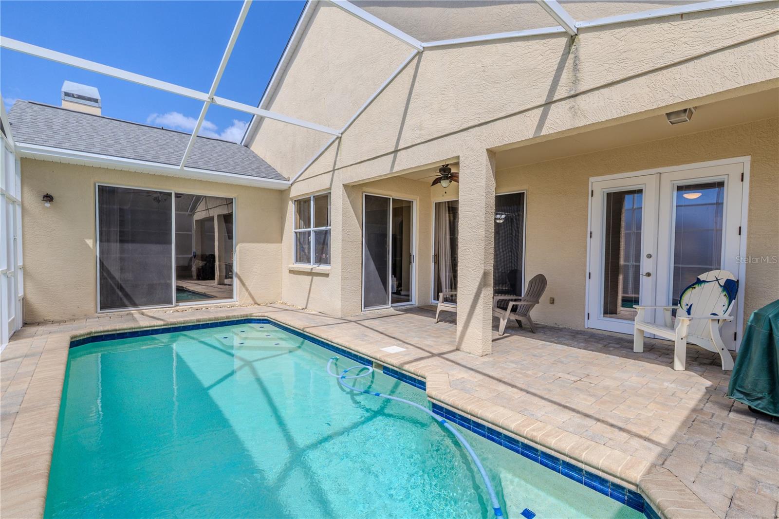 The covered patio is paved and perfect for entertaining, complete with dual ceiling fans and plenty of room for outdoor dining or relaxing by the pool.