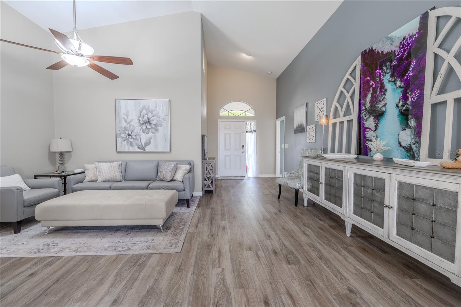 The living room features vaulted ceilings and a ceiling fan with light kit.