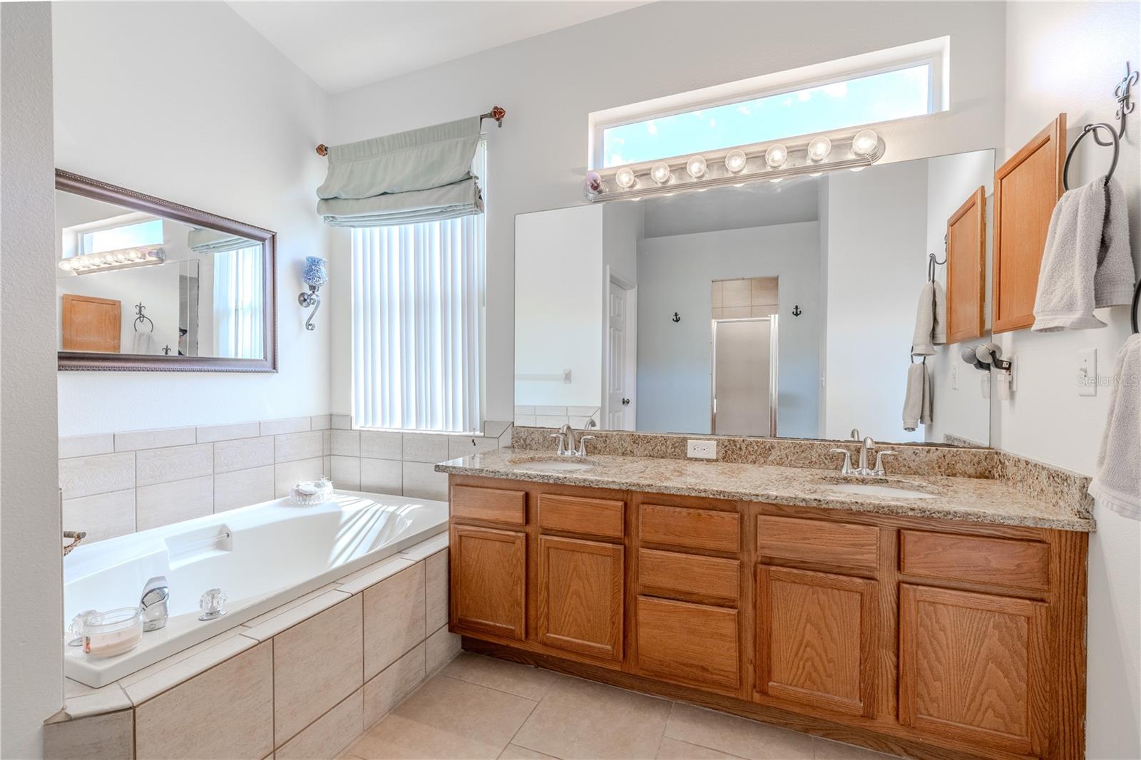 The en-suite bath feels like a personal spa, complete with dual vanities, granite countertops, a garden soaking tub, walk-in shower, private water closet, and plenty of storage.