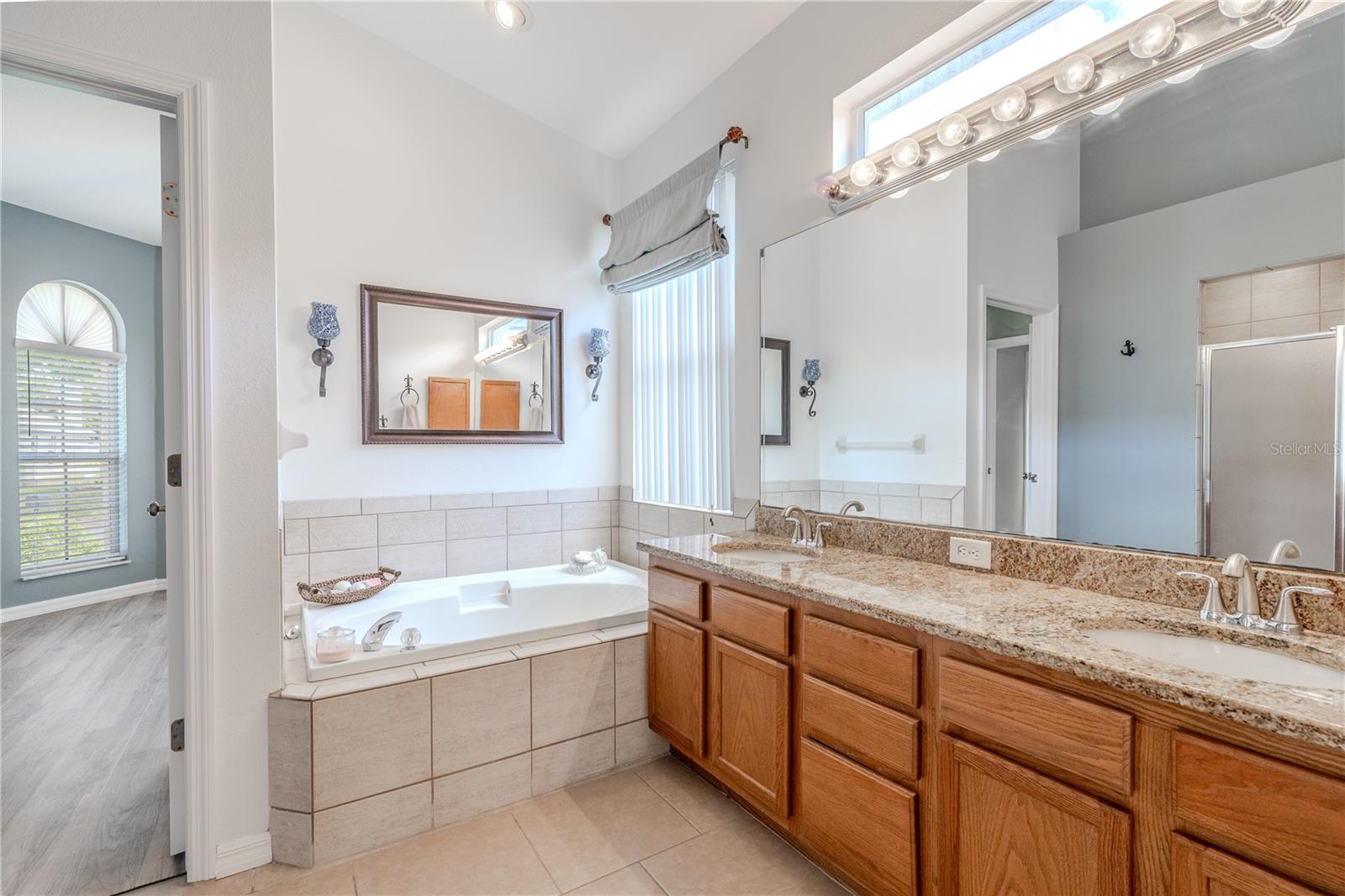 The en-suite bath feels like a personal spa, complete with dual vanities, granite countertops, a garden soaking tub, walk-in shower, private water closet, and plenty of storage.